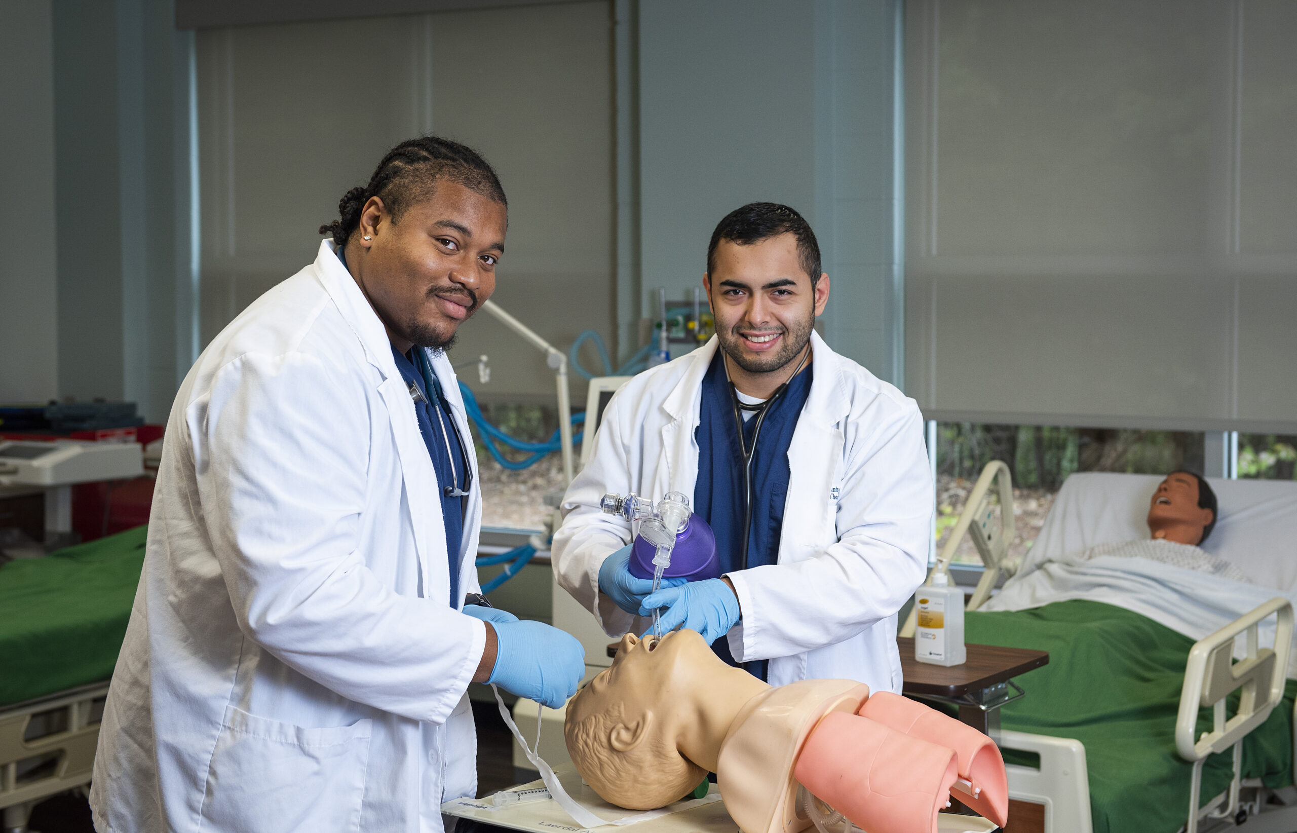 Two medical students practicing on a manikin.