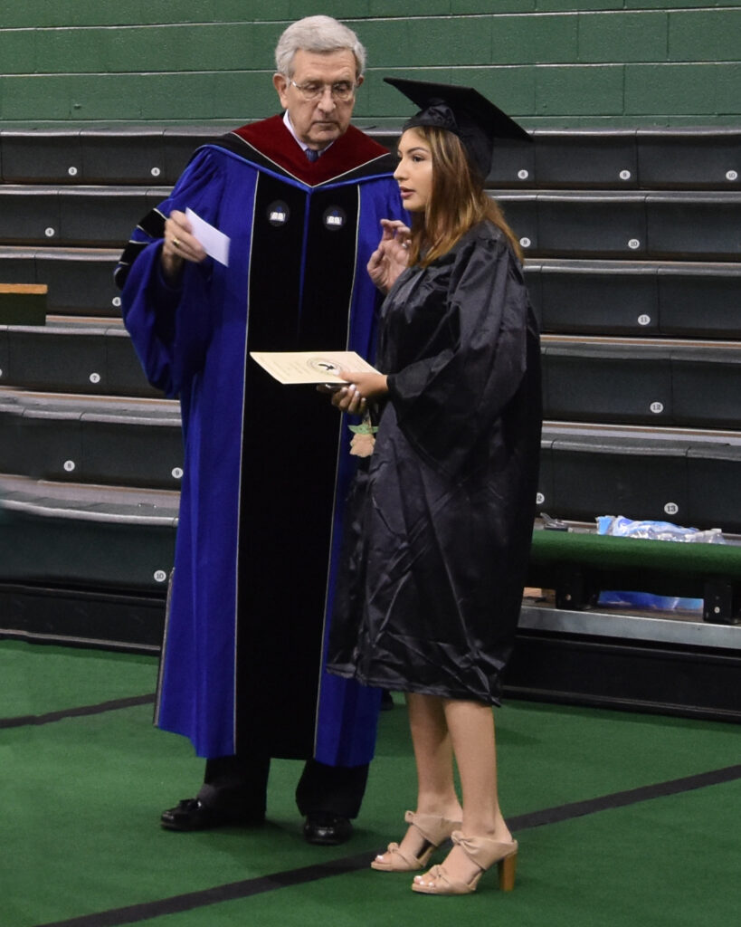 A graduate receives directions of where to walk.
