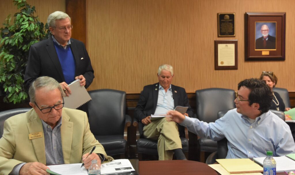 Student Trustee Zane Prusia, at right, speaks with Dr. Bob Lowdermilk, standing, as Trustee Nelson Cole takes notes, and County Commissioner Mark Richardson and RCC Foundation Executive Director Kim Pryor listen in the back.