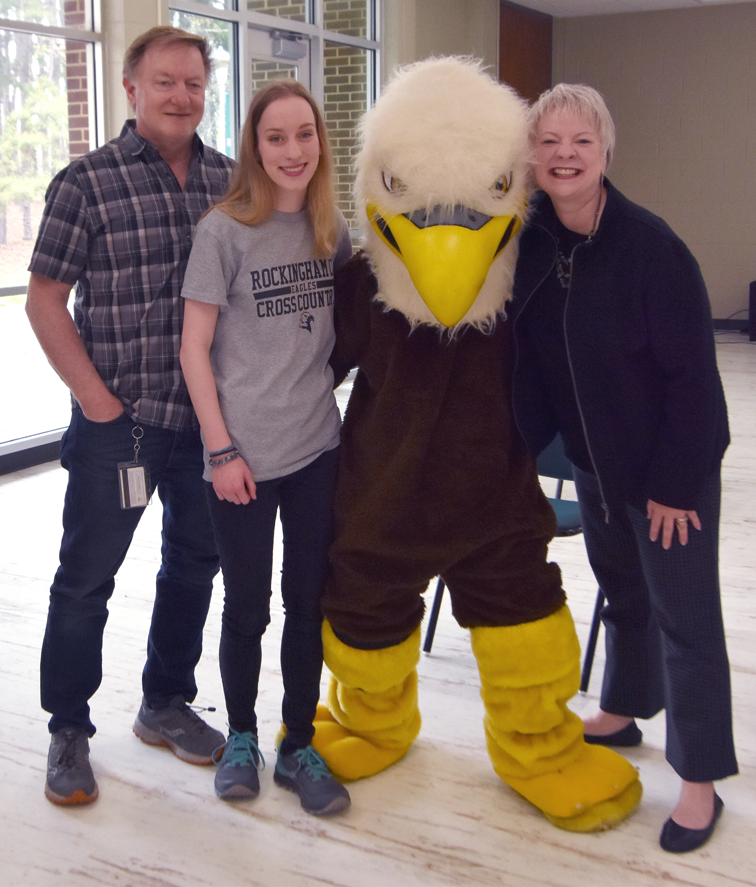 Cross country student athlete with her parents and mascot.