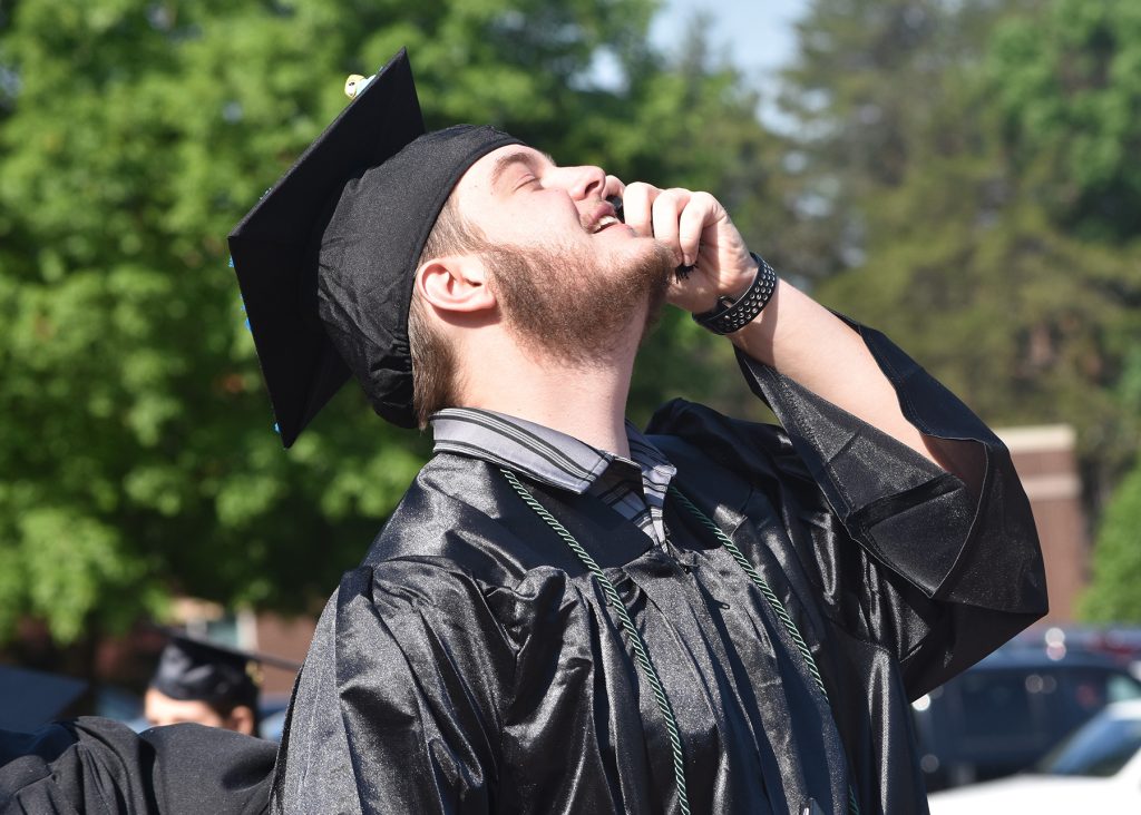 May 2023 RCC graduate shows relief after the ceremony as he talks on his phone.
