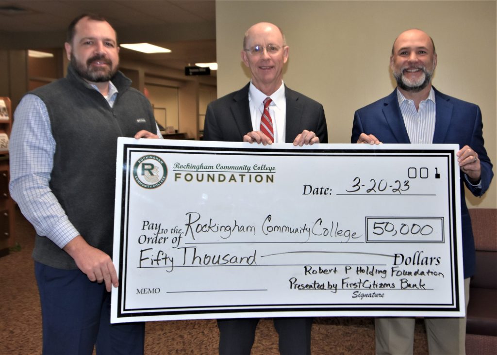 Three men, from First Citizens Bank and RCC, hold a large $50,000 check