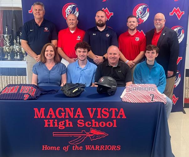 A baseball player sitting at a table surrounded by his family and the coaching staff and principal of Magna Vista High School in Virginia.