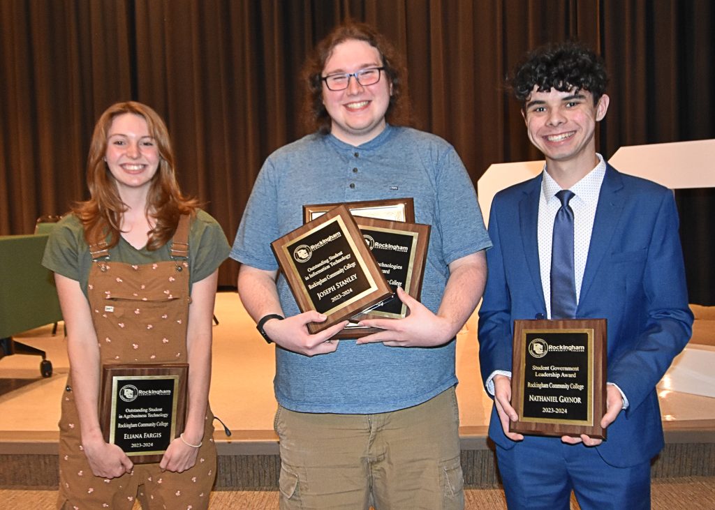 Picture of three students holding plaques.